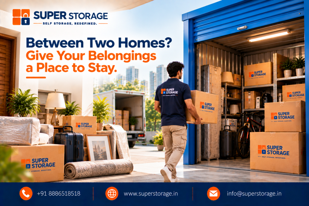 Super Storage banner showing a moving truck and plastic-wrapped household goods outside an illuminated drive-up storage unit as a mover carries a box inside. Headline reads: "Between Two Homes? Give Your Belongings a Place to Stay."